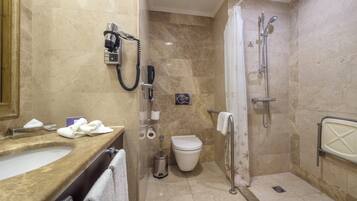 A bathroom with a sink, toilet, shower, and a hand dryer.