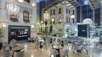 Un vestíbulo amplio con una zona de bar, arreglos de asientos y vistas a una tienda de ropa.
