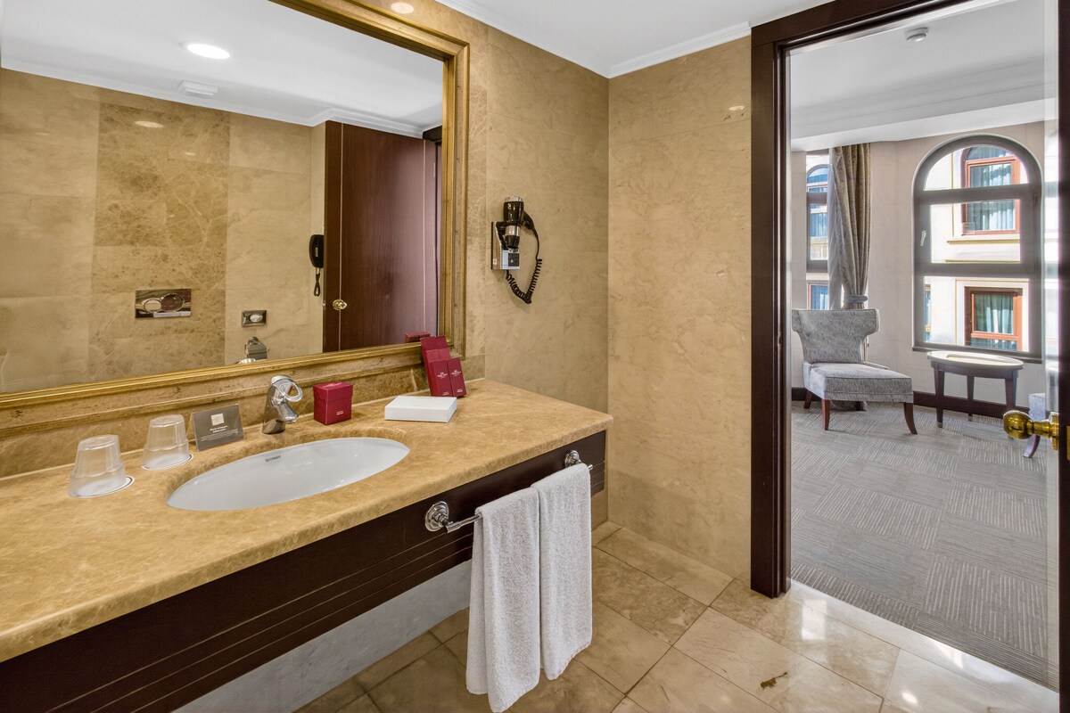Een hotelbadkamer met een grote spiegel, een wastafel, een handdoekrek en een telefoon.