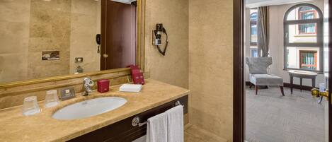 A hotel bathroom with a large mirror, a sink, a towel rack, and a phone.