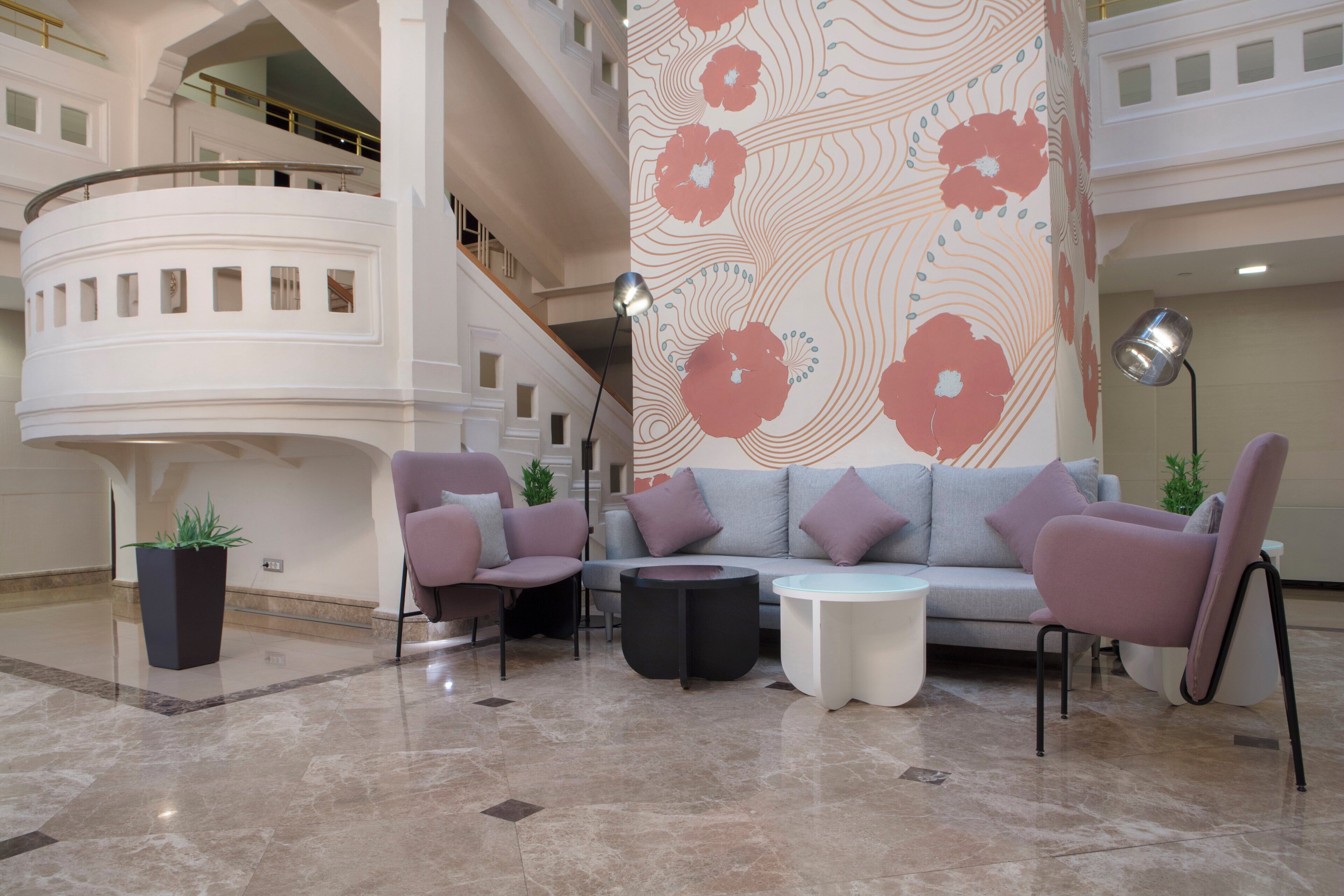 Un vestíbulo con una decoración moderna, que presenta un sofá gris, dos sillones, una mesa de centro y una planta en maceta.