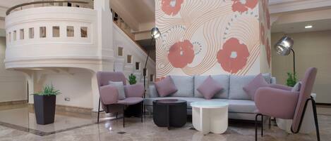 Un vestíbulo con una decoración moderna, que presenta un sofá gris, dos sillones, una mesa de centro y una planta en maceta.