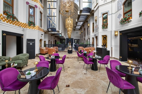 A hotel lobby with a central seating area, multiple doors, and a chandelier.