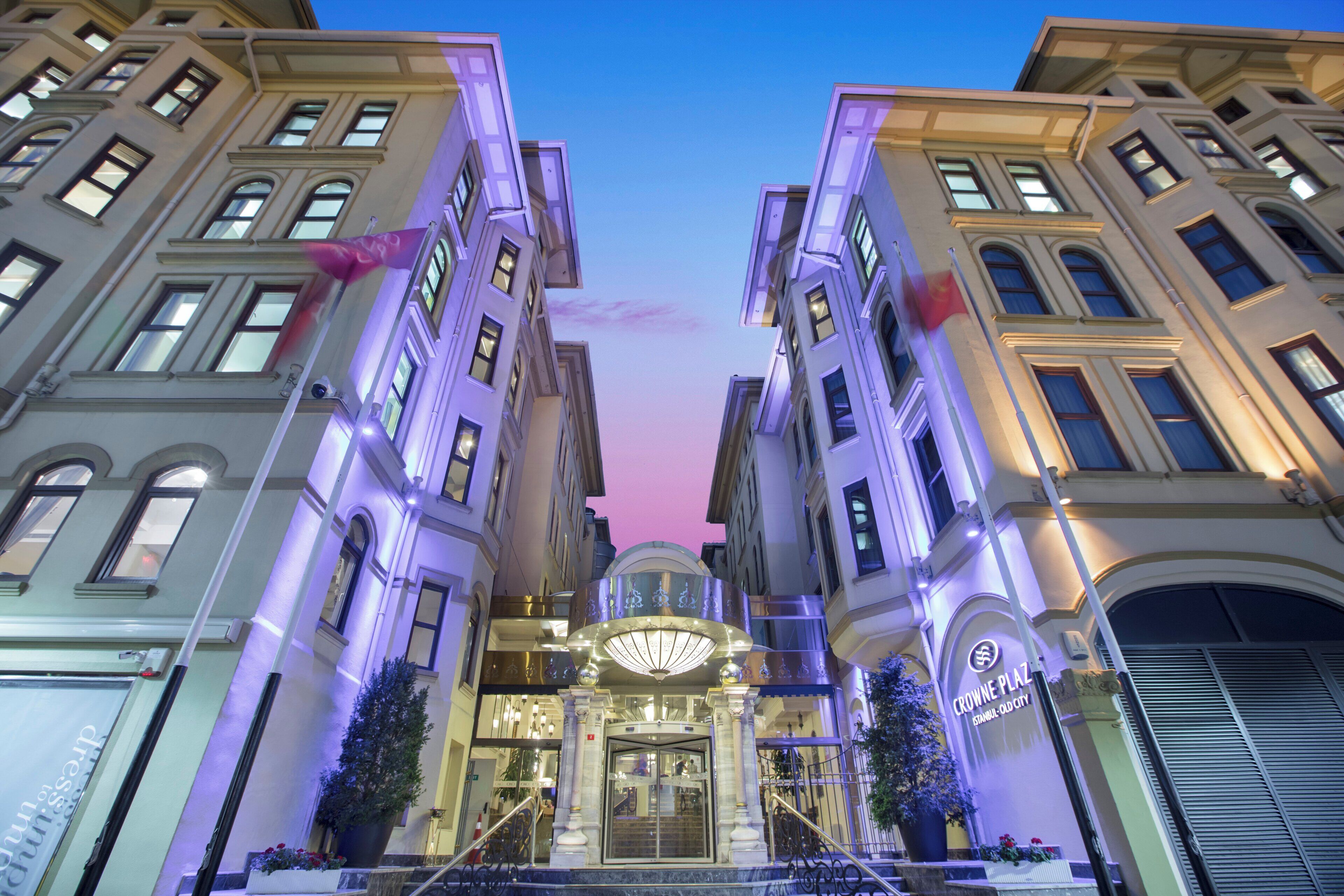 A hotel entrance with a grand staircase, large windows, and a prominent sign.