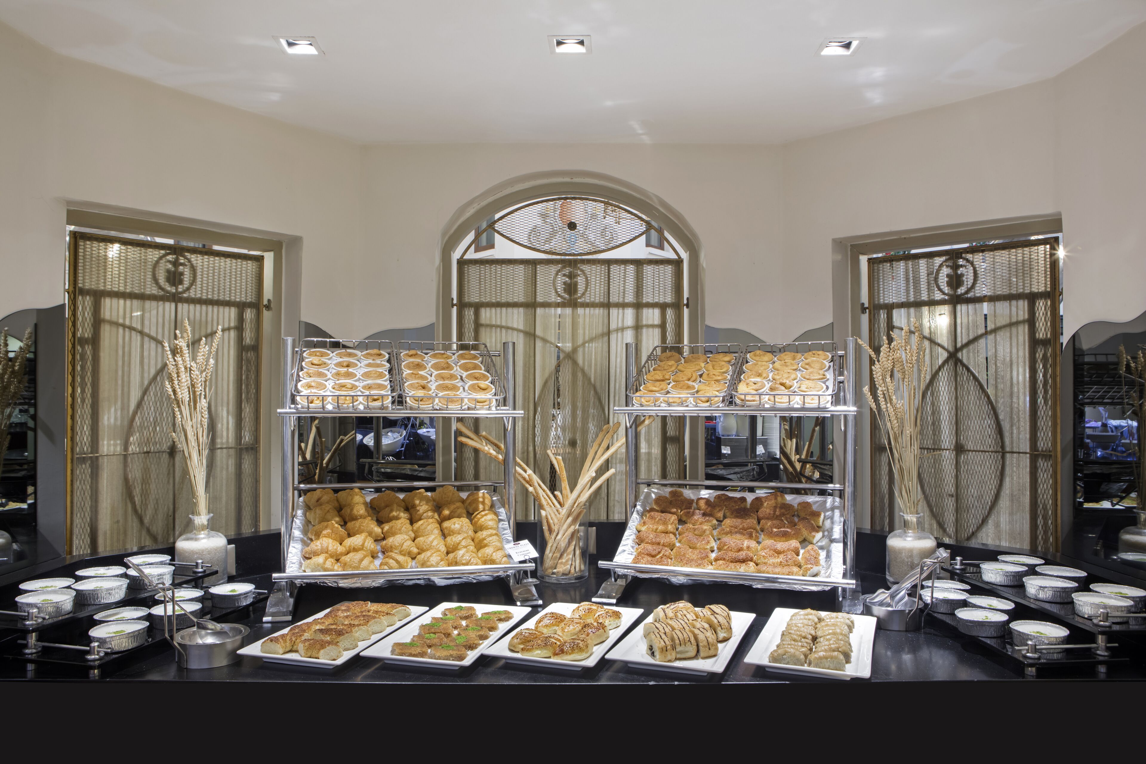 Ein Buffet mit verschiedenen Gebäcken und Desserts, präsentiert in Tabletts und Behältern.