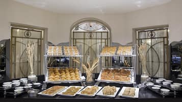 Ein Buffet mit verschiedenen Gebäcken und Desserts, präsentiert in Tabletts und Behältern.