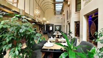 Une salle à manger spacieuse, dotée de hauts plafonds et de lustres modernes.