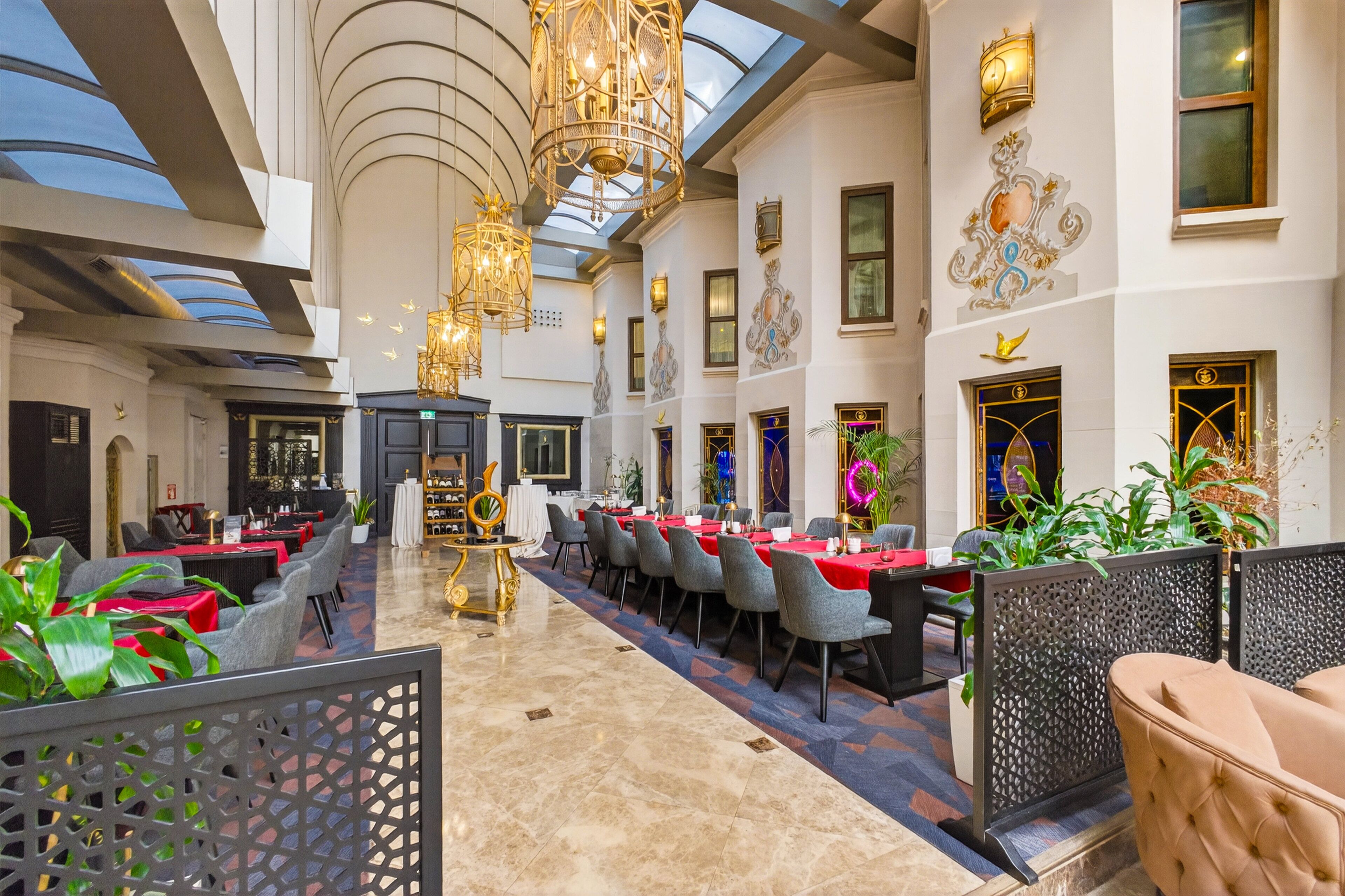 A spacious hotel lobby with a high ceiling, chandeliers, and a central bar area.