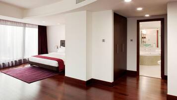 Een moderne hotelkamer met een groot bed, een inloopkast en een badkamer zichtbaar door een geopende deur.