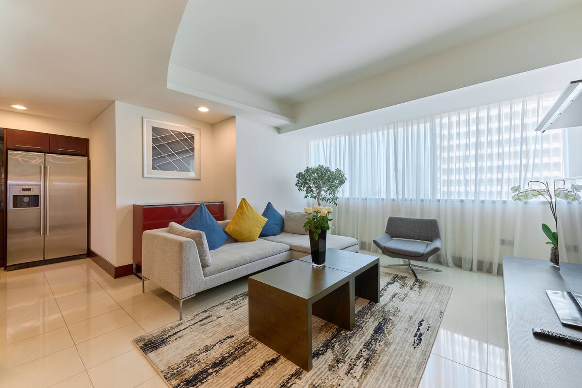 A modern living room with a sofa, coffee table, and a dining area.