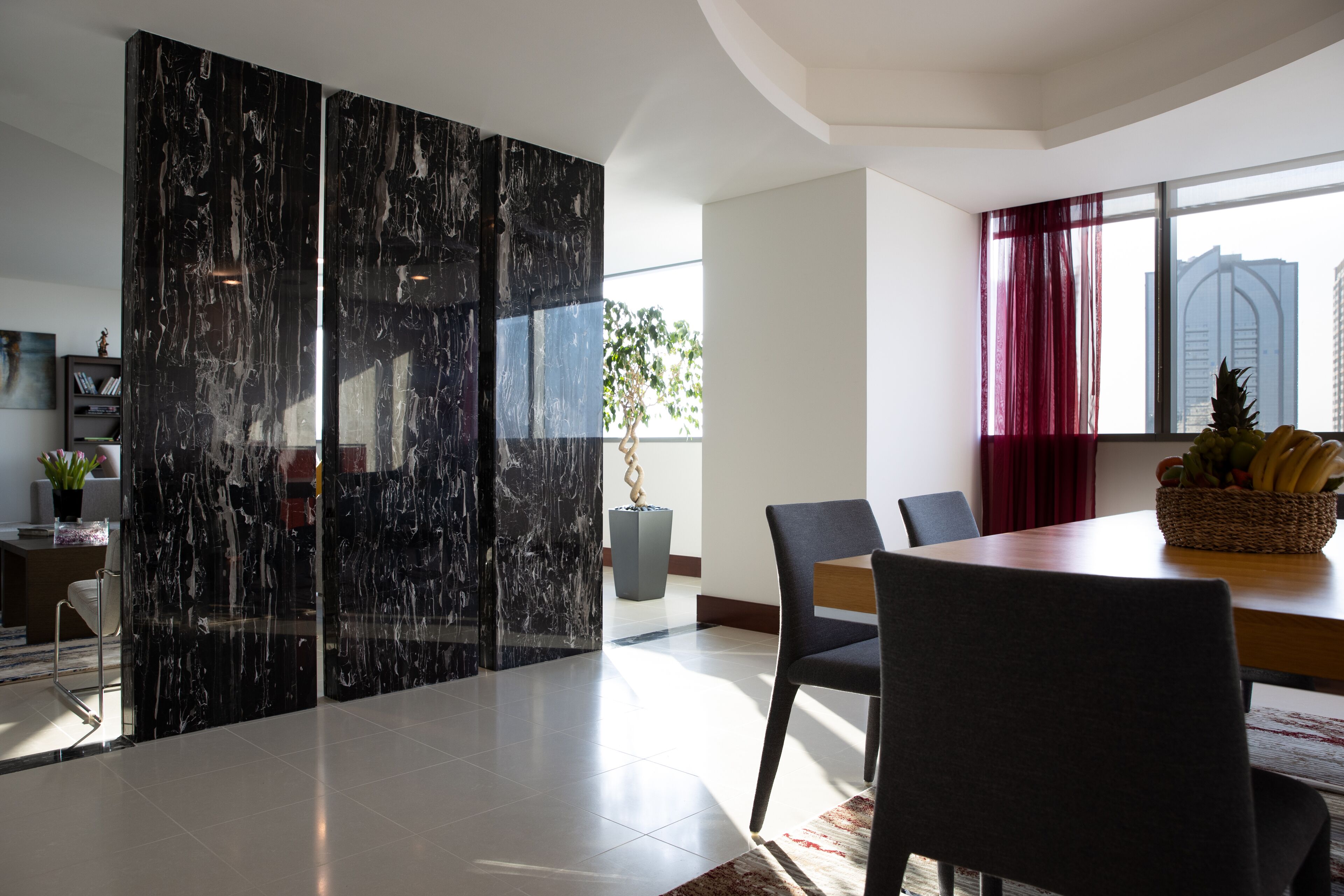 Un comedor moderno con un separador de mármol, una mesa de madera y sillas.