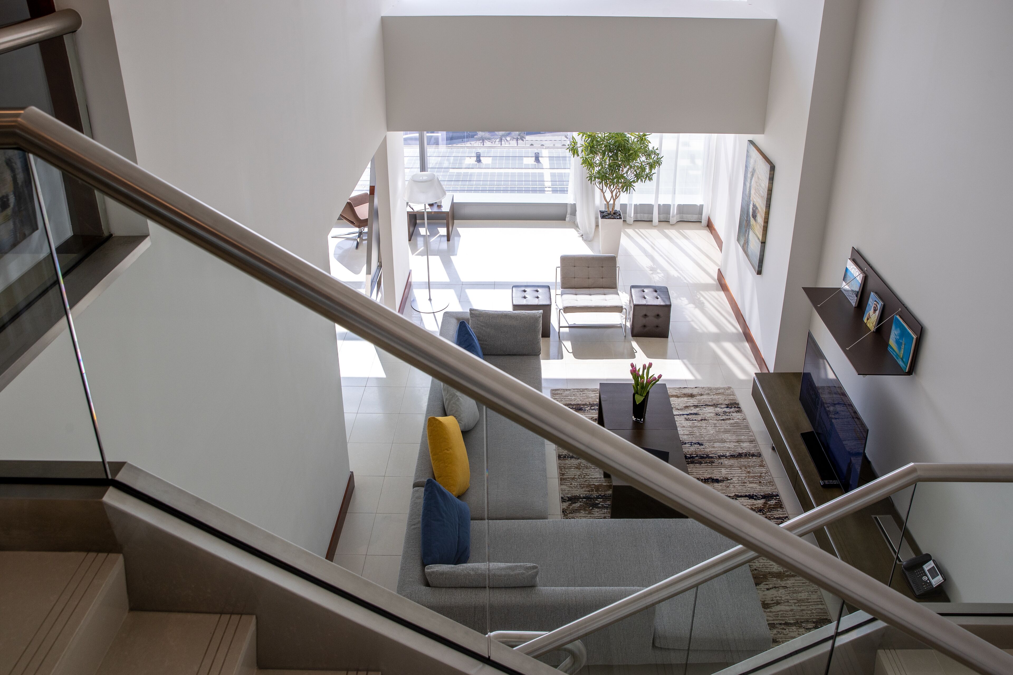 A modern living area with a staircase, a sofa set, a coffee table, and a television.