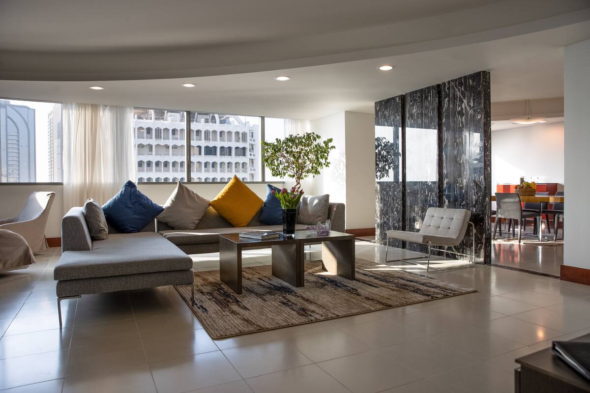 A modern living room with a sofa, coffee table, and a dining area with chairs.
