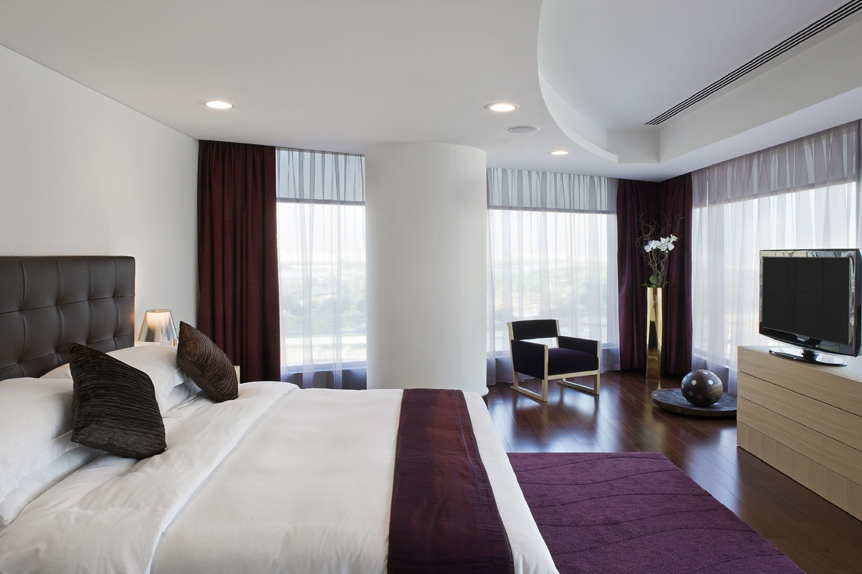 Una habitación de hotel moderna con una cama grande, un televisor, un escritorio y una silla.