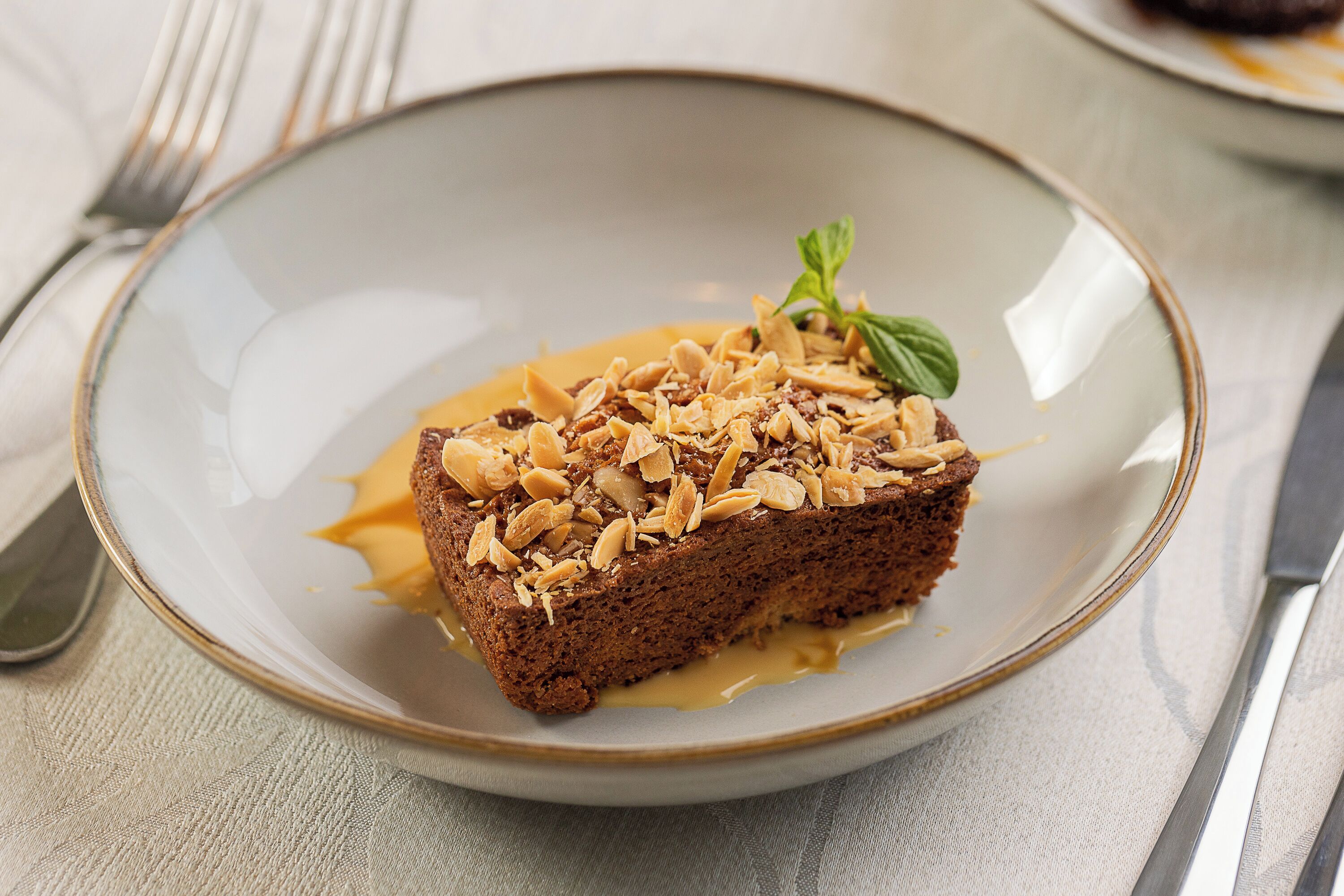 A slice of cake on a plate with a mint garnish.