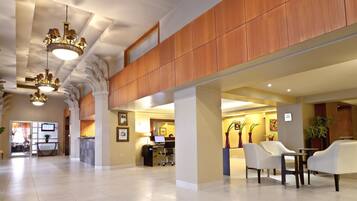 A spacious lobby with high ceilings, wooden paneling, and a reception desk.