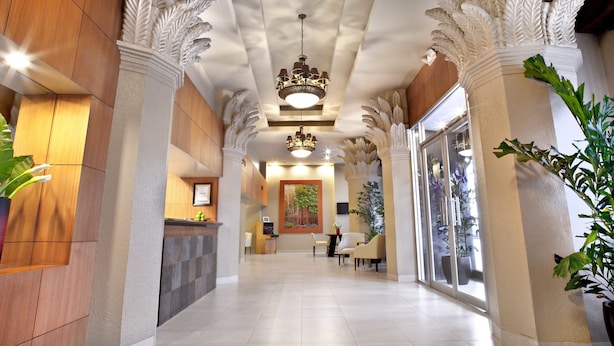 Un hall d’hôtel au design moderne, comprenant un comptoir d’accueil, un espace salon et des colonnes décoratives.