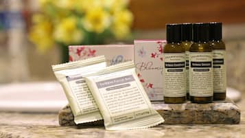 Una encimera de baño con jabón facial, acondicionador y botellas de champú, junto con una caja y sobres.