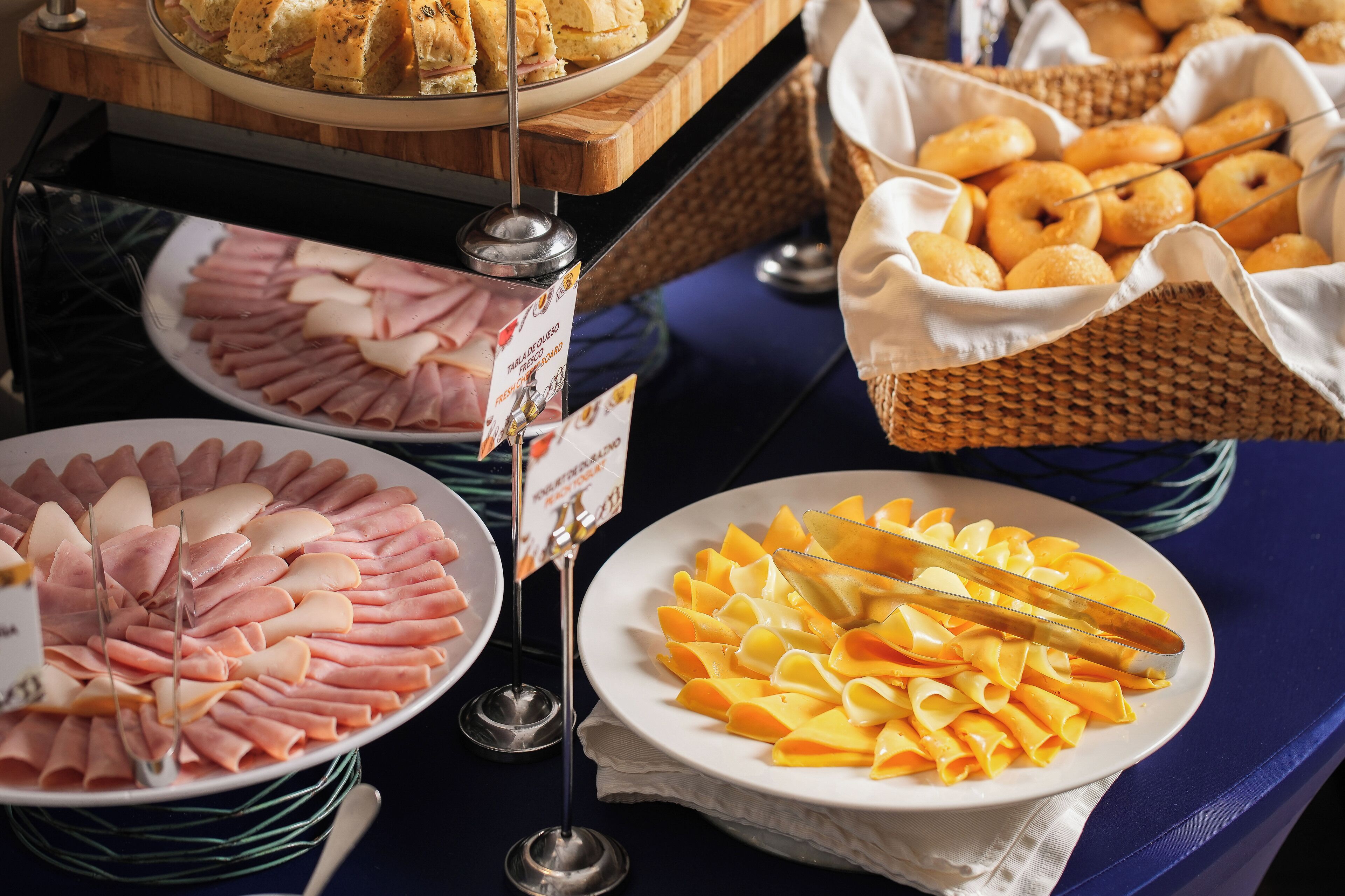 A buffet with various food items including sliced meats, cheeses, and pastries.