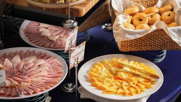 A buffet with various food items including sliced meats, cheeses, and pastries.