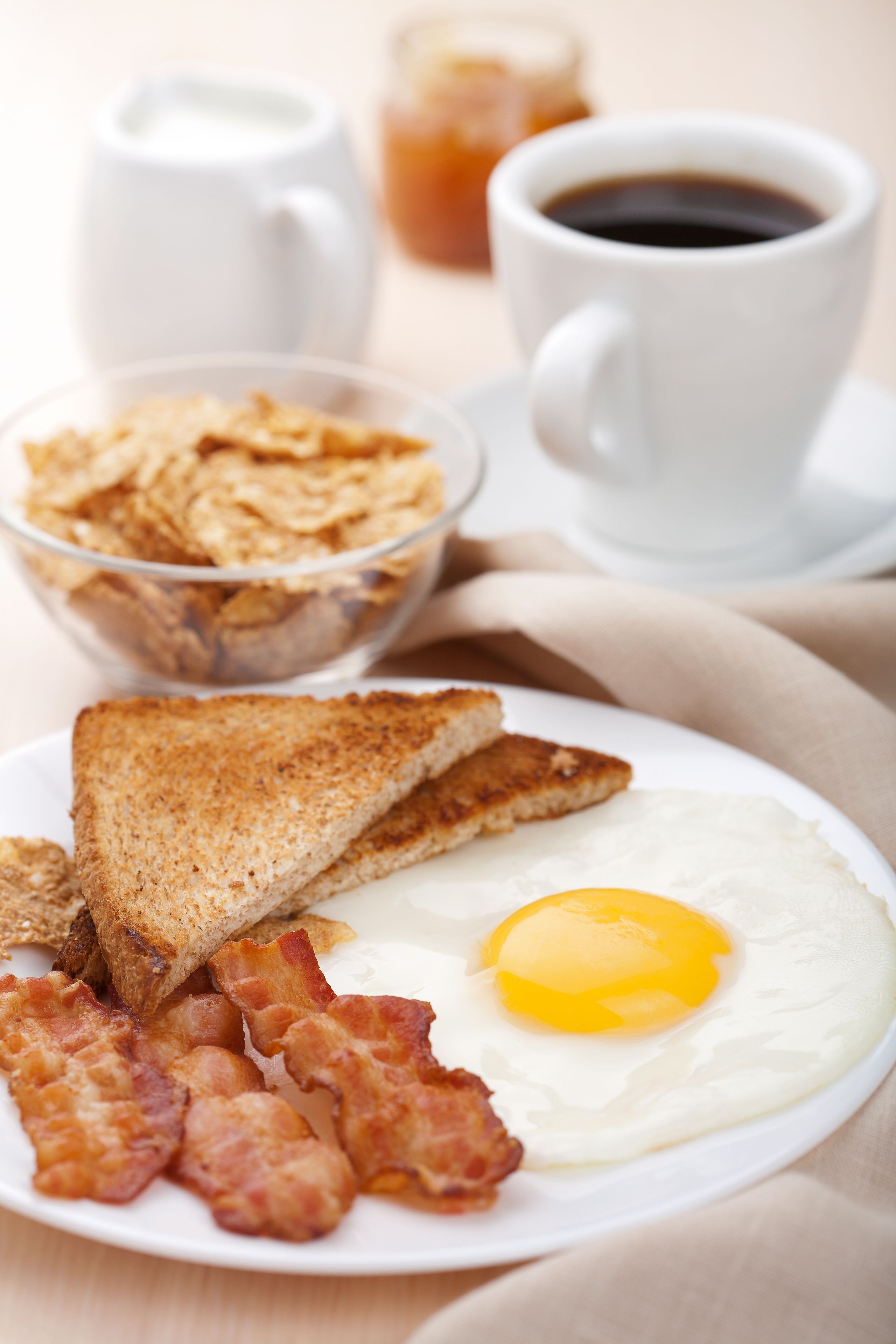 Un plato de desayuno con tostadas, tocino y un huevo frito.