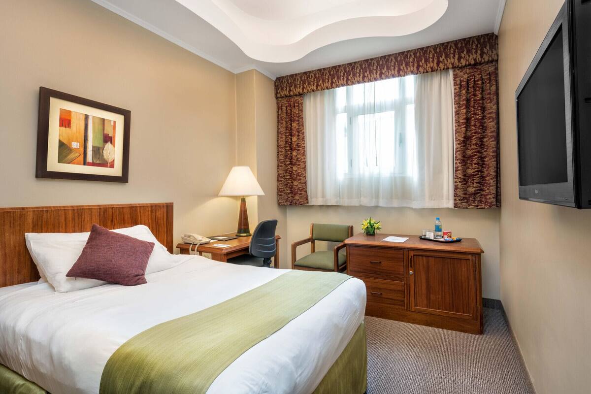 Une chambre d’hôtel équipée d’un lit, d’un bureau, d’une chaise, d’une lampe et d’un téléviseur.
