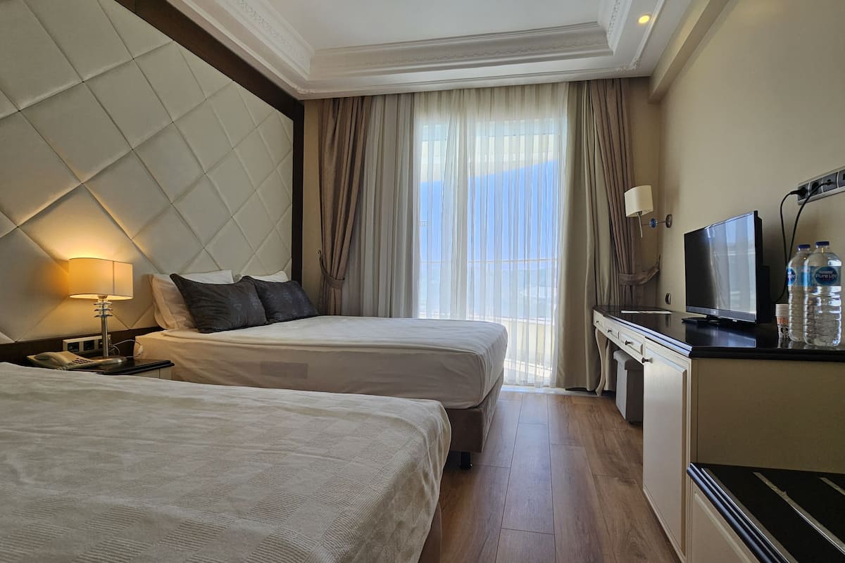 A hotel room with two beds, a desk with a television, and a minibar.