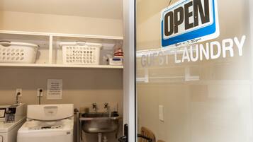 A guest laundry area with a sign indicating it is open from 8am to 7:30pm.