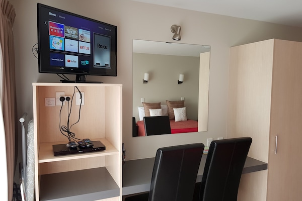 Escritorio, cortinas blackout y tabla de planchar con plancha