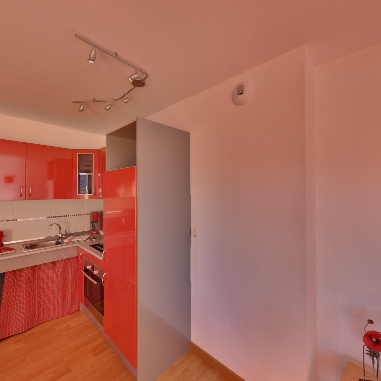 A modern kitchen with red cabinets, a stainless steel sink, and a wooden countertop.