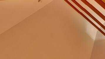 Rincón de una habitación con techo blanco y una estructura metálica roja, posiblemente parte de una escalera o soporte.
