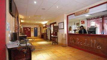 A reception area with a wooden counter labeled "Accueil" and "La Pradella."