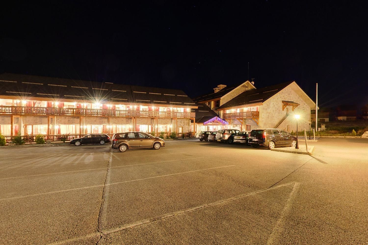 Un hotel de varios pisos, estacionamiento y entrada bien iluminada.