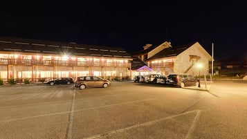 Un hotel amb diverses plantes, un aparcament i una entrada ben il·luminada.