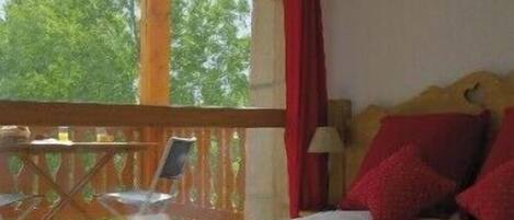 Un dormitorio con cama, una mesita y una silla en un balcón.