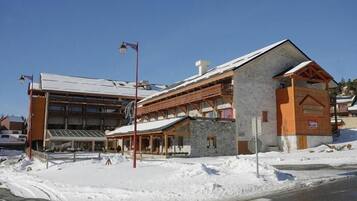 A building with a stone facade, a wooden balcony, and a covered entrance.