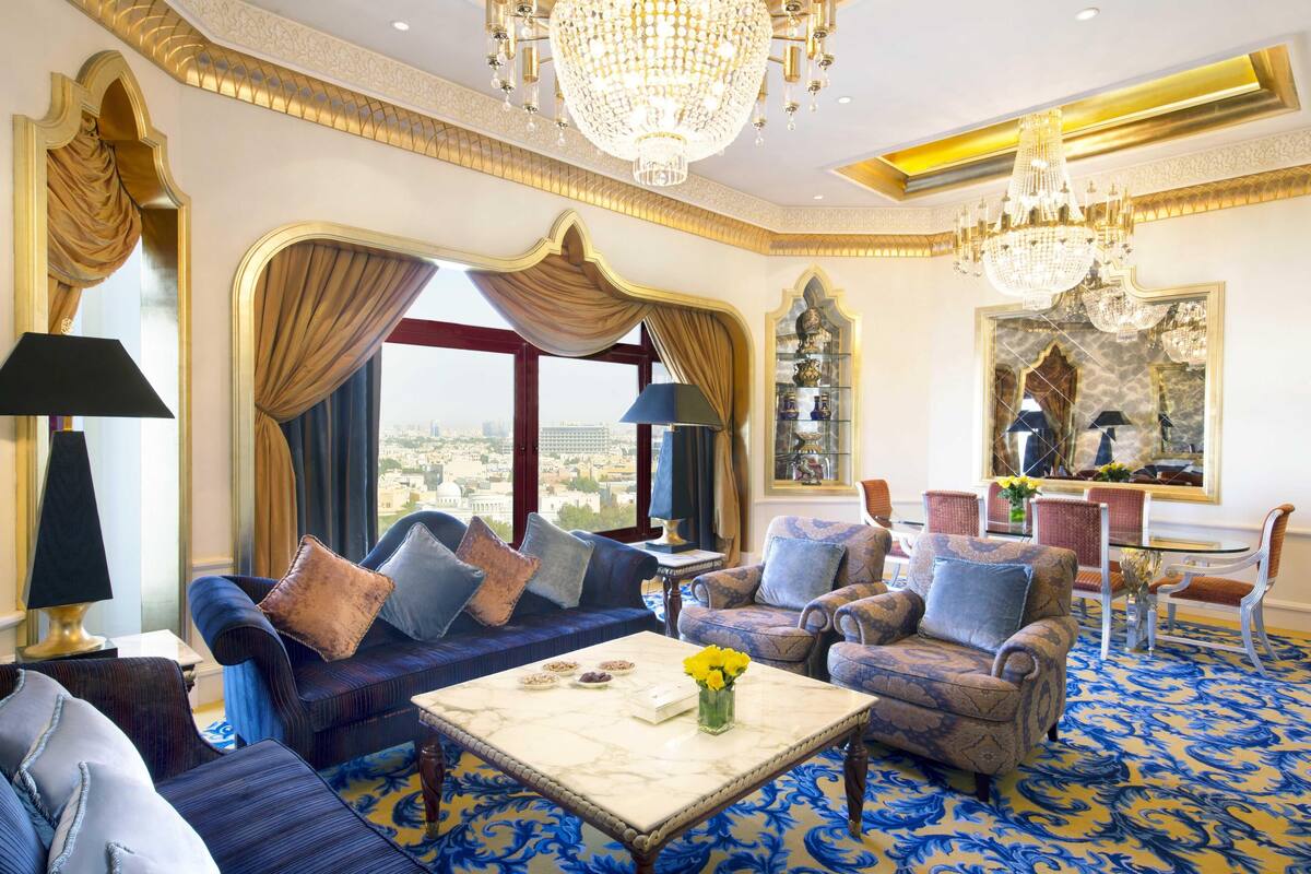 A luxurious living room with a blue patterned carpet, a marble coffee table, and elegant furniture.
