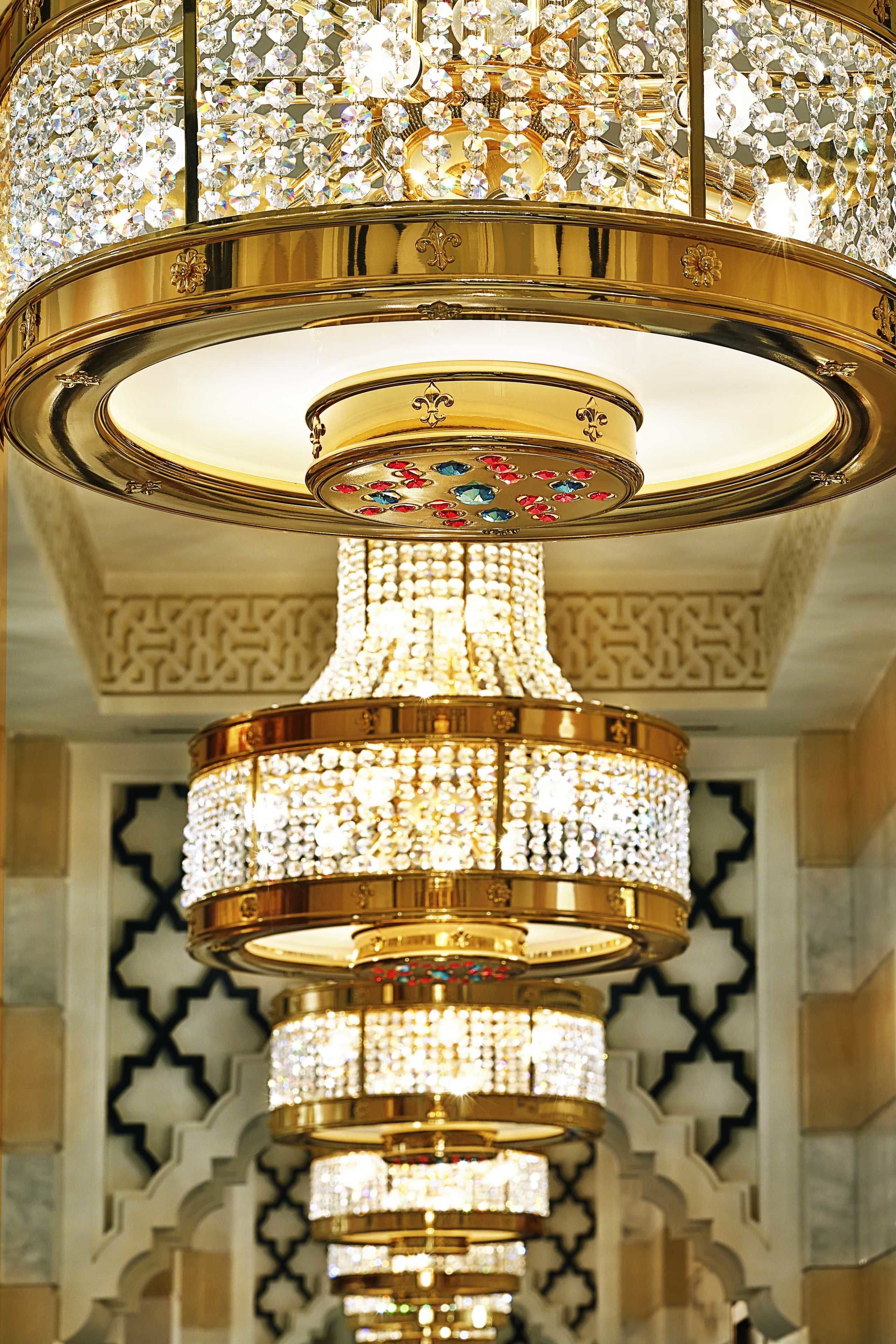 Un lustre à plusieurs niveaux, orné de cristaux et de motifs dorés.