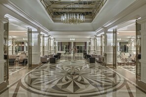 A spacious lobby with a geometric marble floor, elegant chandeliers, and seating areas. - Delphin Diva Premiere Hotel - All Inclusive (Antalya)