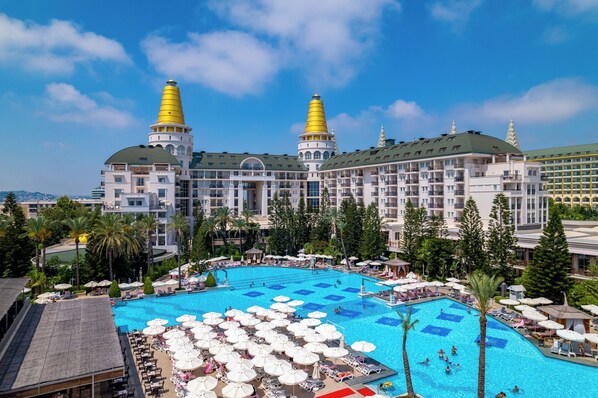A hotel with a large swimming pool surrounded by lounge chairs and umbrellas, and two prominent yellow spires. - Delphin Diva Premiere Hotel - All Inclusive (Antalya)