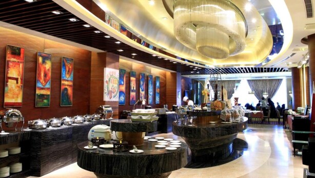 A modern hotel lobby with a central round bar, artwork on the walls, and a chandelier. - Wenjin Hotel (Beijing)