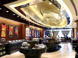 Un moderno vestíbulo de hotel con un bar circular central, obras de arte en las paredes y un candelabro.