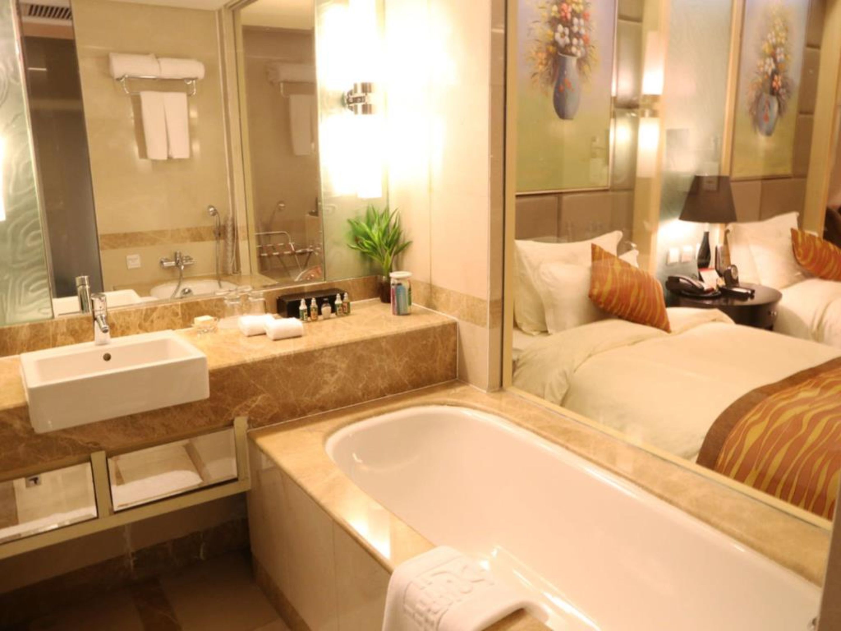 A hotel bathroom with a sink, mirror, and bathtub.