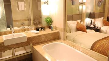 A hotel bathroom with a sink, mirror, and bathtub.