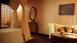 A bathroom with a bathtub, a mirror, and a round table with candles. - Wenjin Hotel (Beijing)