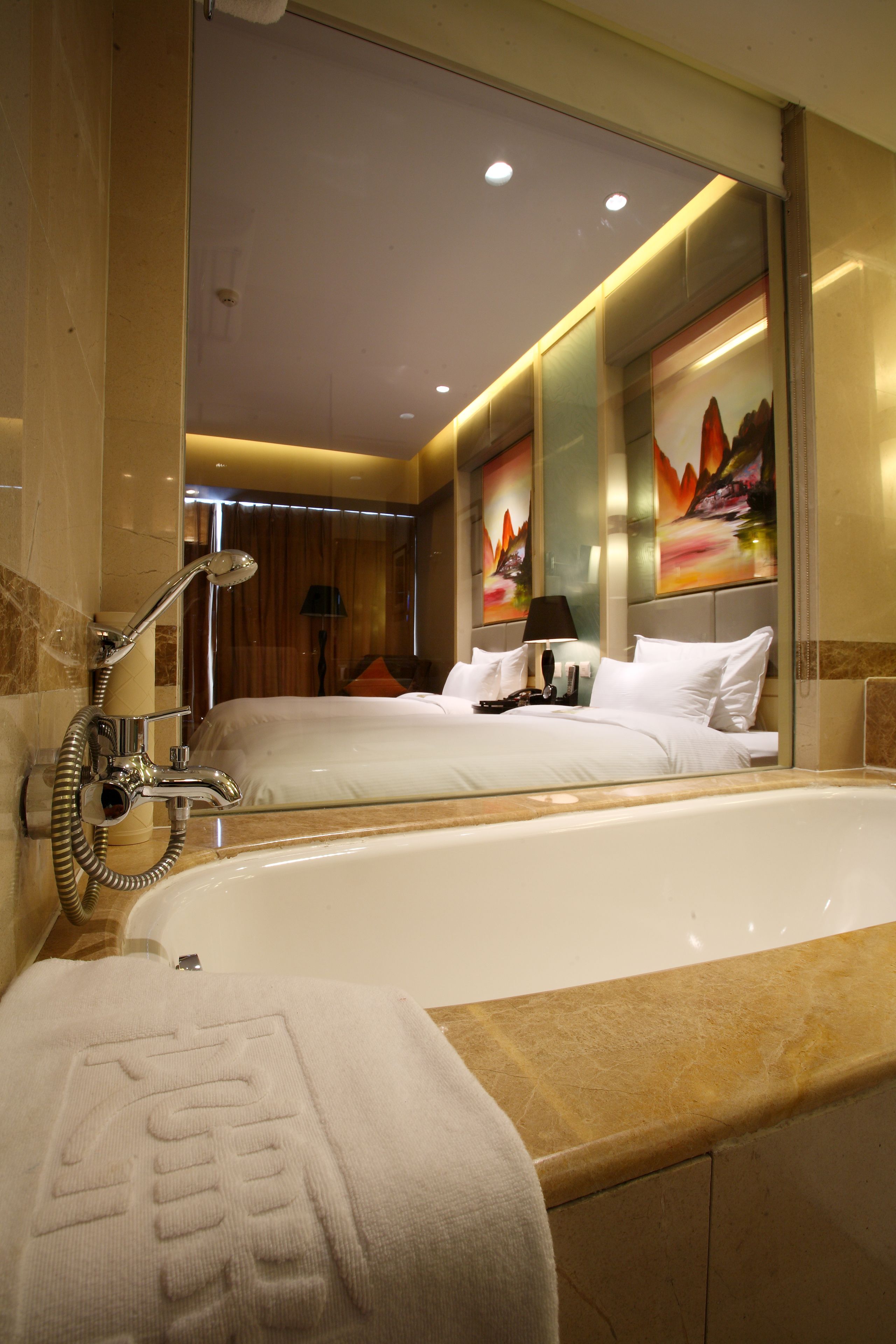 A modern hotel bathroom with a large bathtub, a shower, and a mirror reflecting the room.