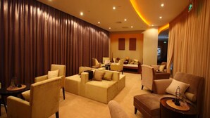 A spacious lounge area with multiple seating options, including sofas and armchairs, arranged around a central coffee table. - Wenjin Hotel (Beijing)
