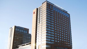 A tall hotel building with multiple floors and a large glass facade. - Wenjin Hotel (Beijing)