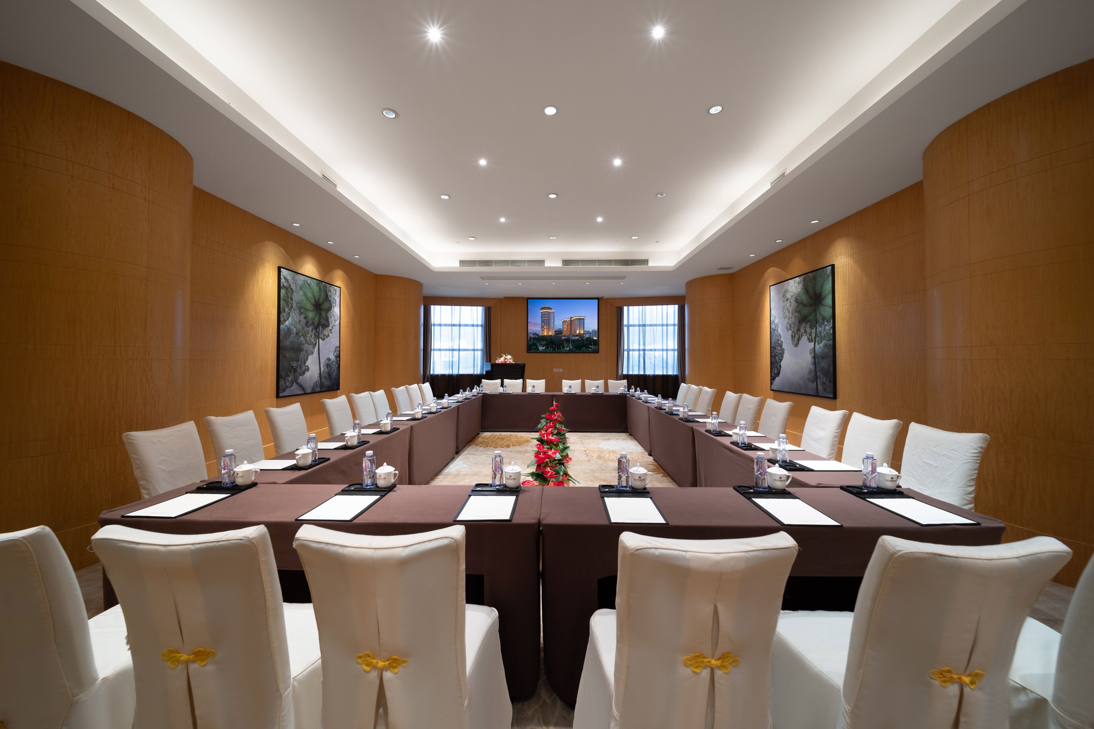 A conference room with a long table, white chairs, and a Christmas tree.