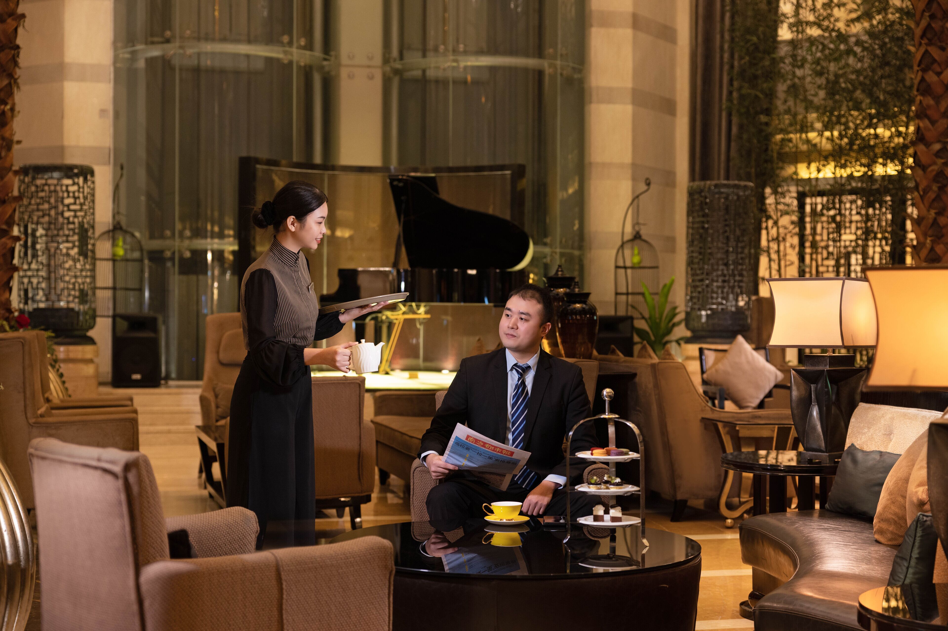A luxurious lobby with a grand piano, comfortable seating, and a coffee table with a tray.